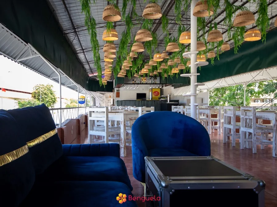 Espaço lounge com poltronas azuis e bar ao fundo